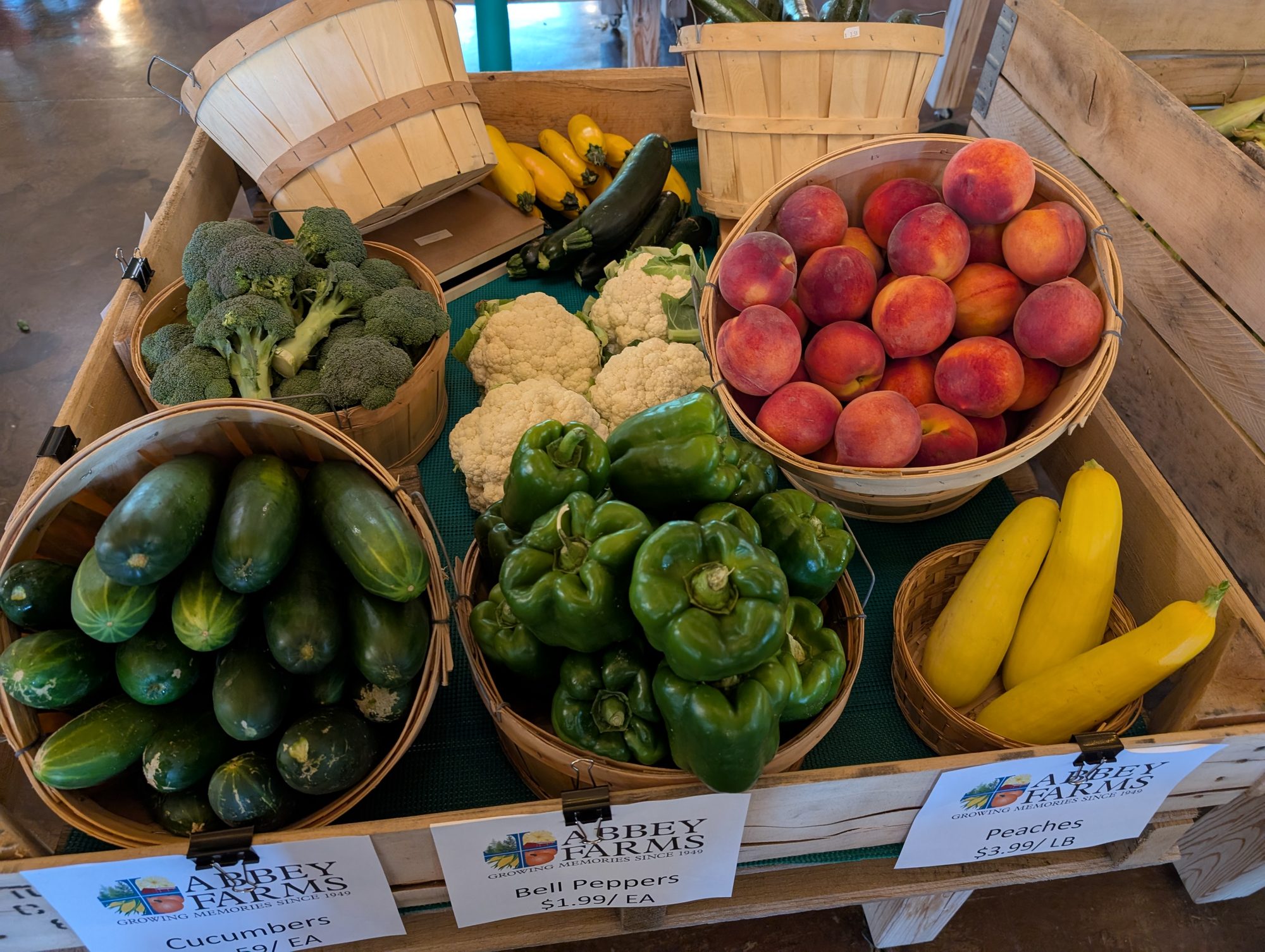 Bushel baskets of peaches, cucumbers, peppers, squash, broccoli and cauliflower at the Abbey Farms produce stand